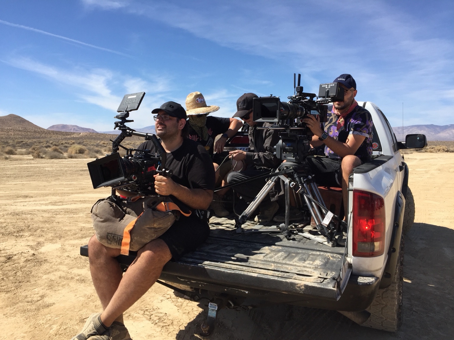 Crew and cameras gathered on the back of a white pickup in the desert